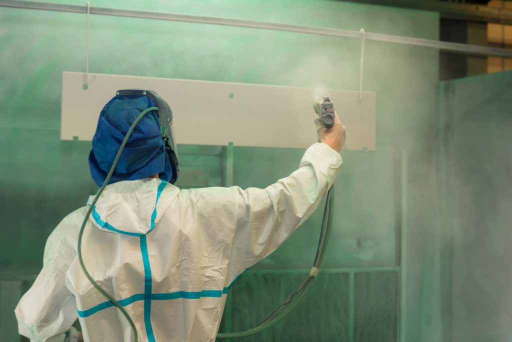 A man spray painting plastic within a paint booth
